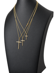 Three sizes of solid 10K gold cross pendant necklaces on a black jewelry display — angled view