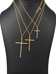 Three sizes of solid 10K gold cross pendant necklaces on a black jewelry display — close-up