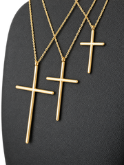 Three sizes of solid 10K gold cross pendant necklaces on a black jewelry display — pendant detail
