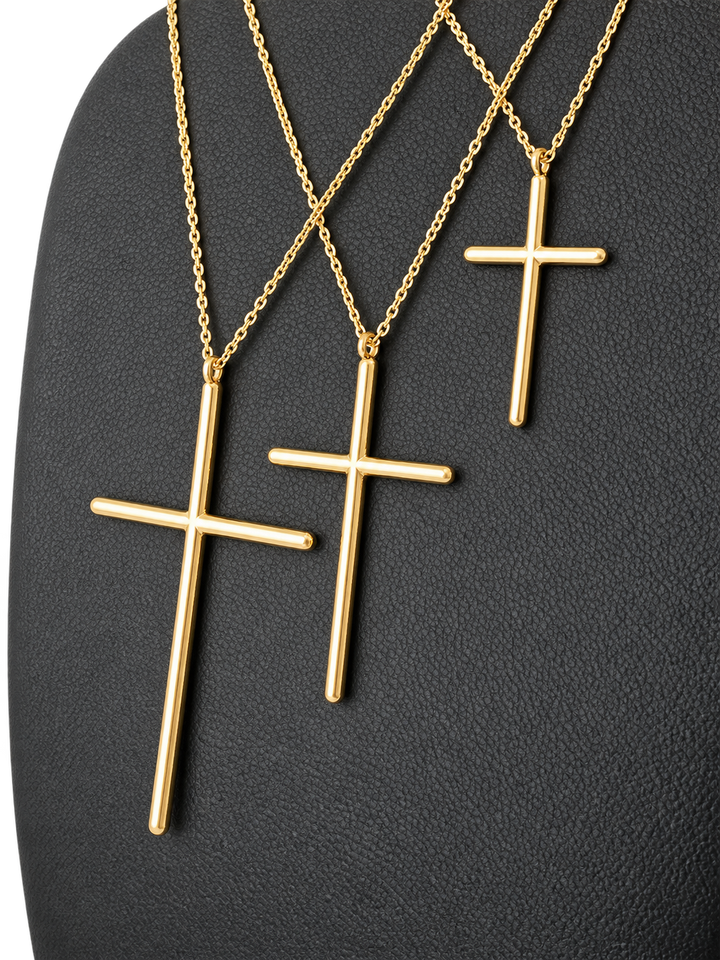 Three sizes of solid 10K gold cross pendant necklaces on a black jewelry display — pendant detail