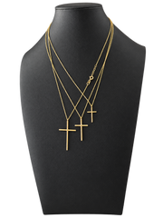 Three sizes of solid 10K gold cross pendant necklaces on a black jewelry display — front view