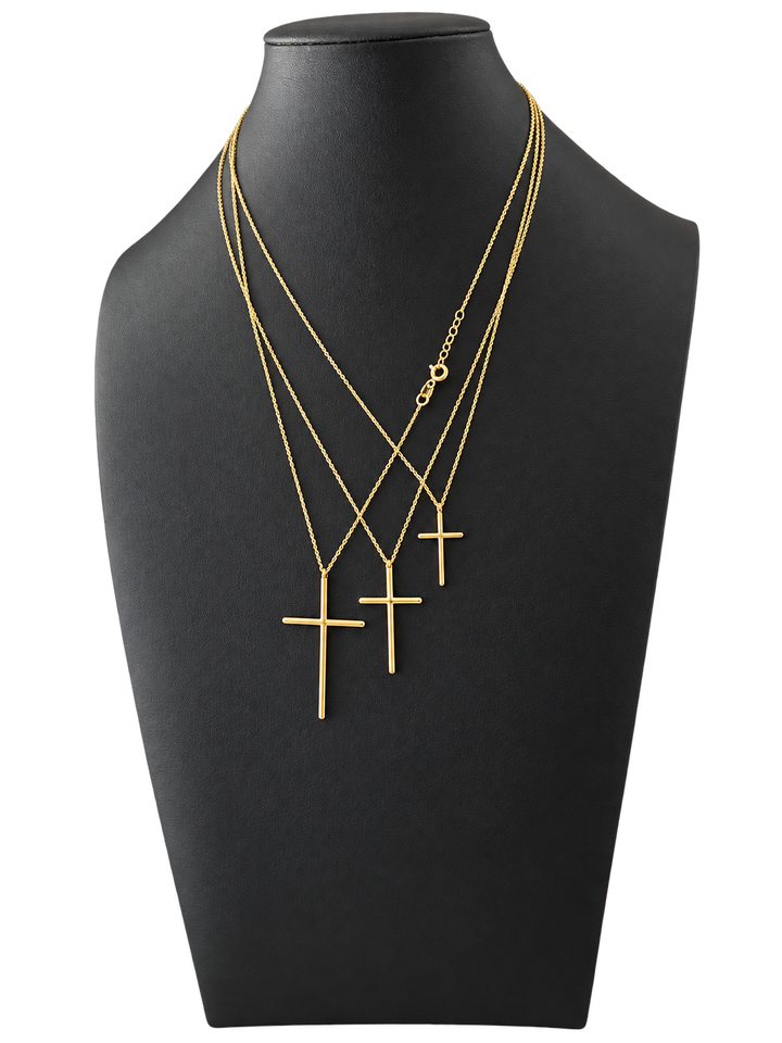 Three sizes of solid 10K gold cross pendant necklaces on a black jewelry display — front view