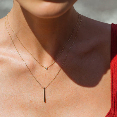 layered 14K gold bar pendant necklace on model with delicate chains and small round accent