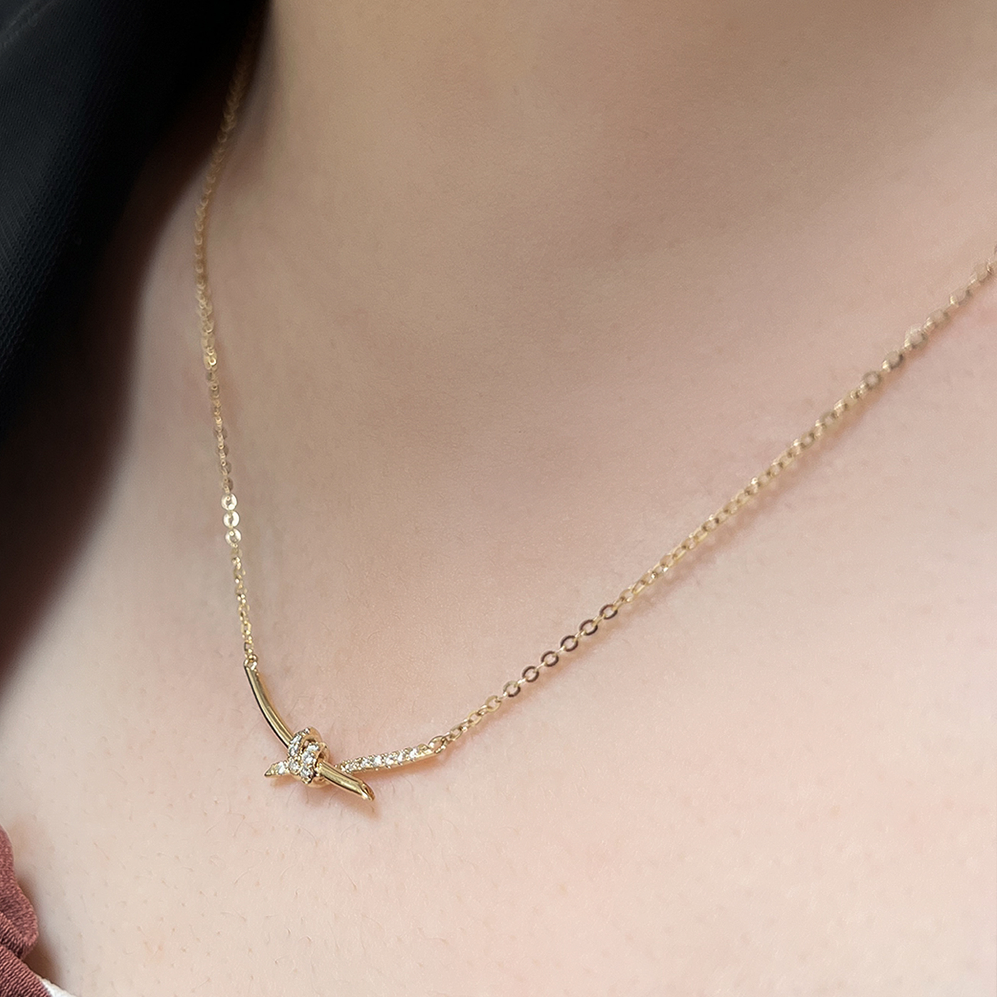 14K gold diamond knot necklace on model with delicate chain and small sparkling knot pendant