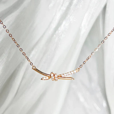 14K gold diamond knot necklace delicate knotted bar pendant with small diamonds on fine chain