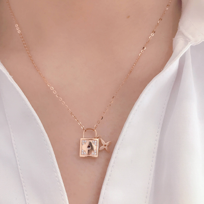 14k diamond lock necklace in rose gold with small padlock and star charm on delicate chain over white blouse